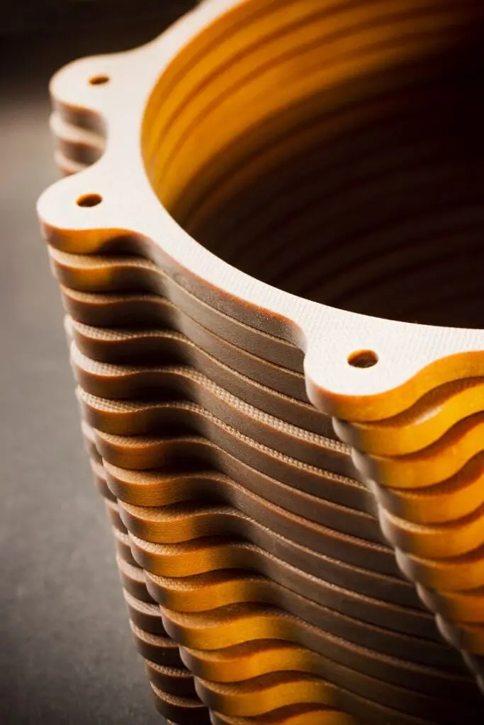 Stack of wavy-edged circular plates with bolt holes, featuring a Polyimide Glass laminate, viewed from above at an angle.