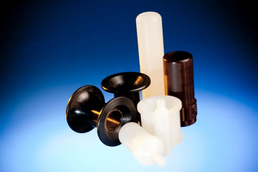 Assorted plastic industrial components made from thermoplastic materials displayed on a blue gradient background.