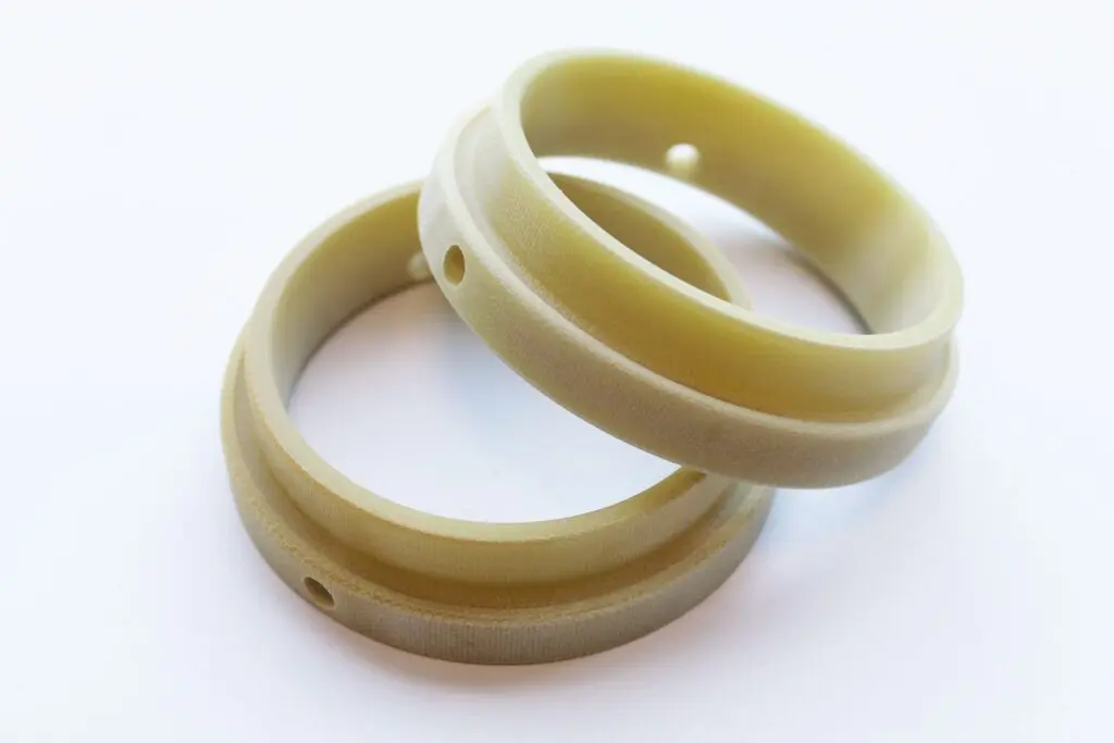 Two beige plastic SRBGF rings with small holes, overlapping each other on a white background.