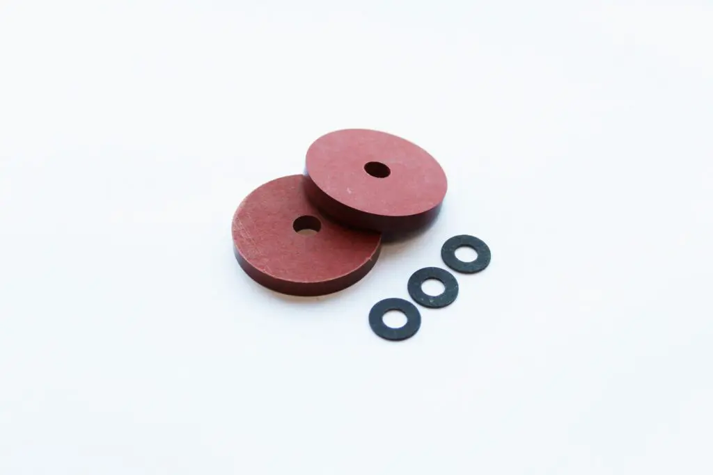 Two large red washers made from Vulcanised Fibre sheet and three small black washers are displayed on a white background.