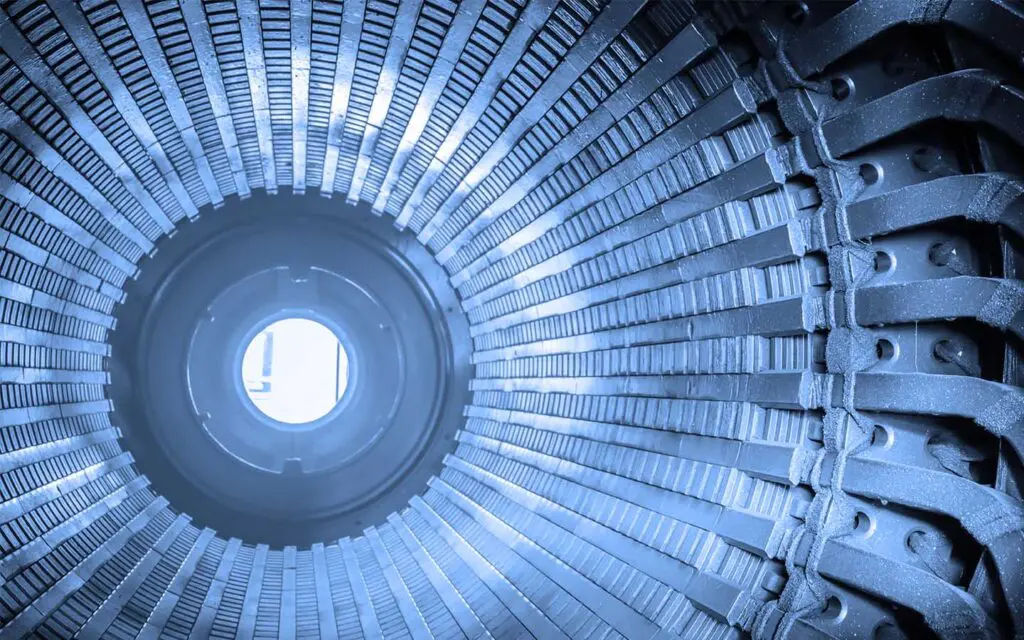 Interior view of a large industrial metal cylinder with evenly spaced ridges, shown in blue tones.