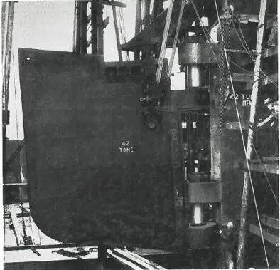 A large metal object labeled “42 tons” is suspended by cables and machinery on an industrial site.