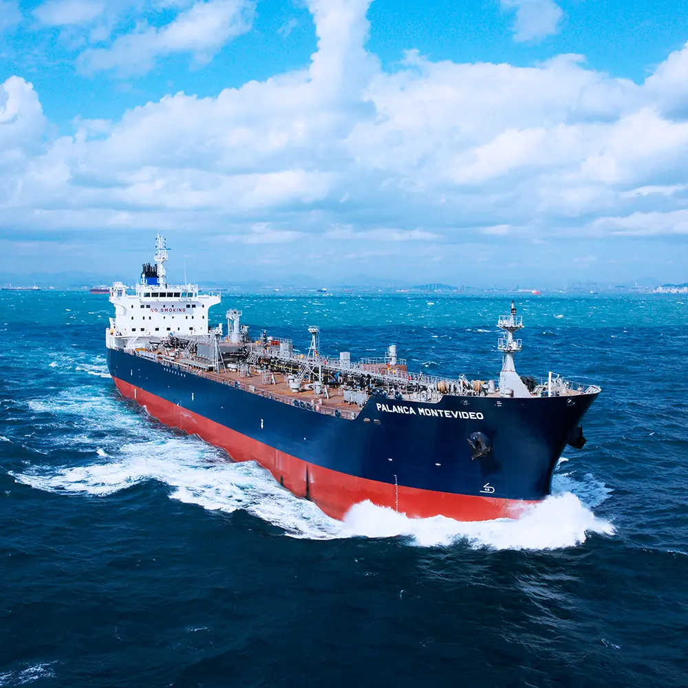 Large cargo ship named PALANGA MONTEVIDEO, built with advanced non-metallic engineering materials, sails through the blue ocean under a partly cloudy sky.