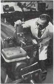 Pioneer George Ellison in a lab coat operates a large industrial machine.